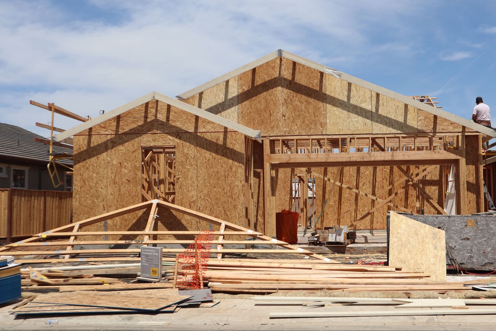A new house at the framing stage, a worker on the frame.