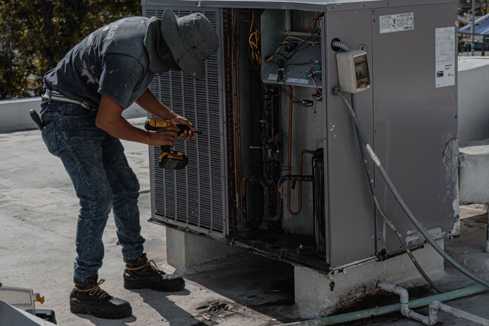 A technician working on an air conditioning unit on a rooftop.