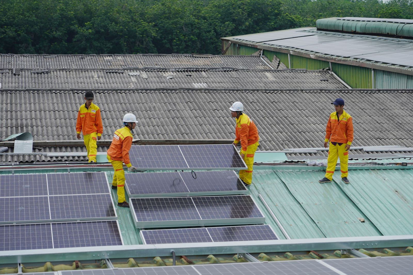 A crew in safety gear installing solar panels on a roof.